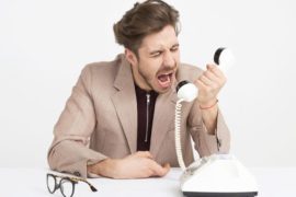 man-wearing-brown-suit-jacket-mocking-on-white-telephone-1587014