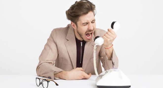 man-wearing-brown-suit-jacket-mocking-on-white-telephone-1587014