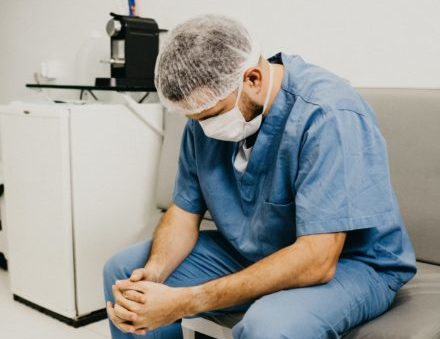 man-wearing-blue-scrub-suit-and-mask-sitting-on-bench-3279197